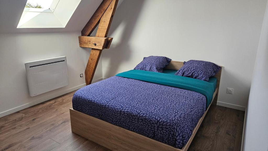 - une chambre avec un lit doté de draps violets et une fenêtre dans l'établissement Charmant f3, à Villers-Carbonnel