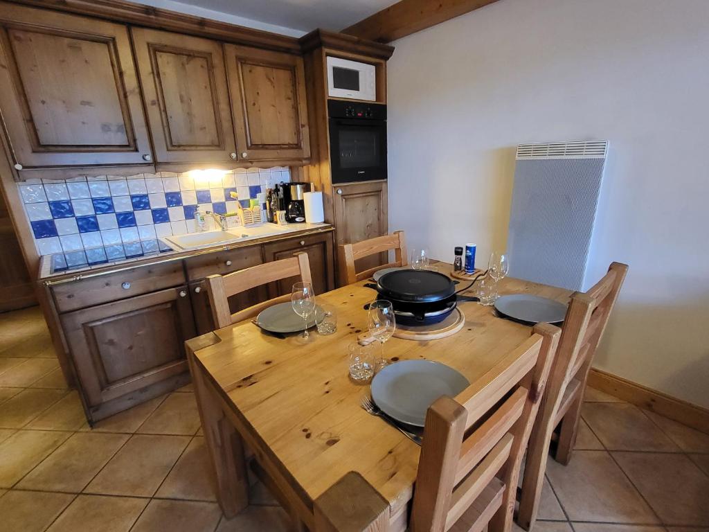 een keuken met een houten tafel met borden en glazen bij Ecrins A4, 2 bedroom apartment, central Samoëns in Samoëns