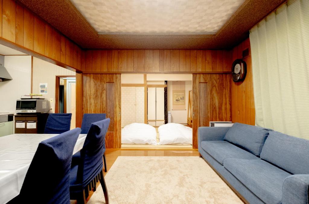 HDO Furano Garden House في فورانو: غرفة معيشة مع أريكة زرقاء وسرير
