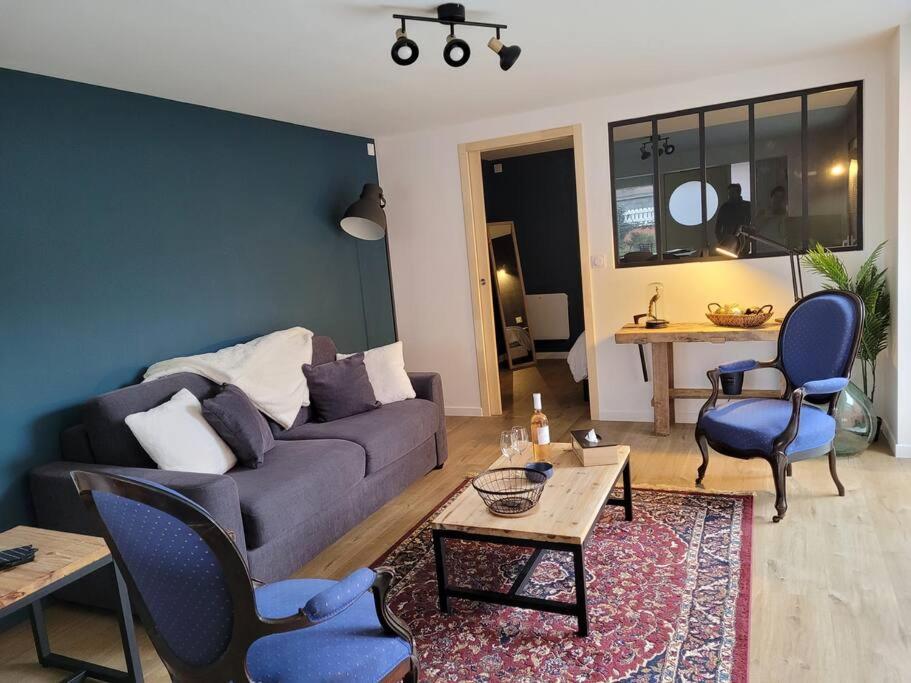 een woonkamer met een bank, stoelen en een tafel bij L'atelier, appart avec jardin à 100 m de la mer. in Donville-les-Bains