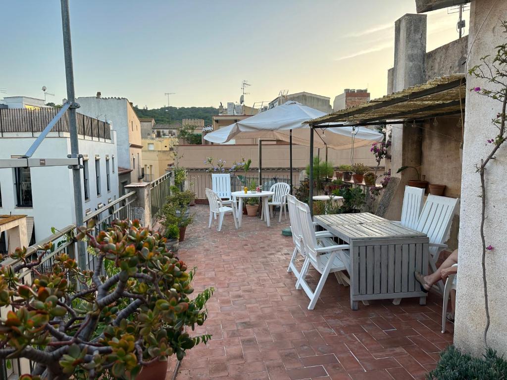 a patio with white chairs and tables and an umbrella at NOTARIA-Apartamento y Estudio en casco antiguo, al lado de playa, Rambla y Monasterio, con acceso a terraza ajardinada in Sant Feliu de Guixols