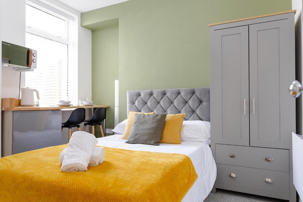 a bedroom with a bed with a yellow blanket at Bay City Studio Apartments in Cardiff