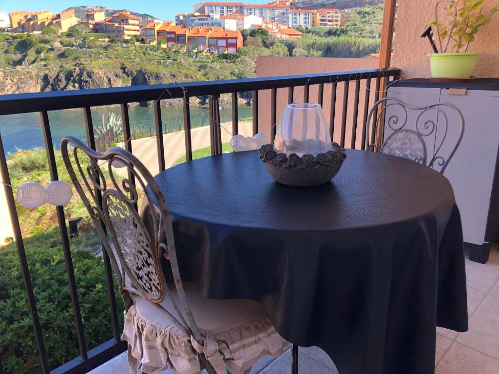 - une table noire avec un verre sur le balcon dans l'établissement Appartement vue mer les pieds dans l'eau, à Collioure