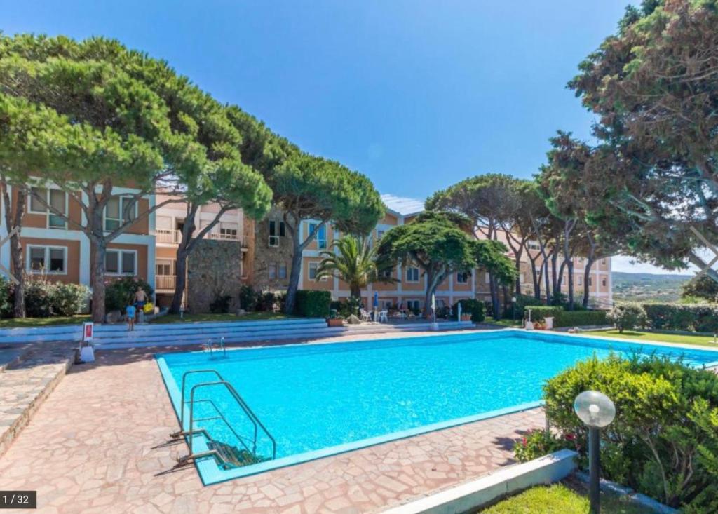 - une piscine dans une cour avec des arbres et des maisons dans l'établissement Recidence gallo di Gallura Casa Azzurra, à Santa Teresa Gallura