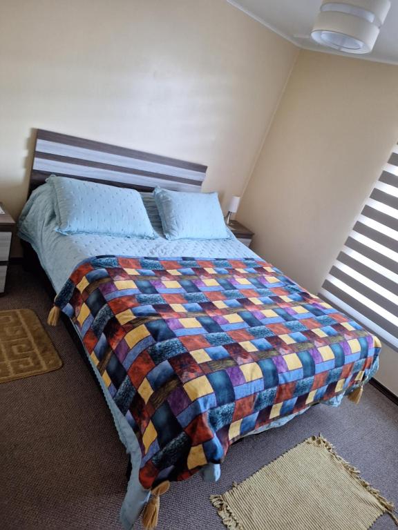 a bedroom with a bed with a colorful quilt on it at CABAÑA MI CASA AMOBLADA EN PUERTO MONTT in Puerto Montt