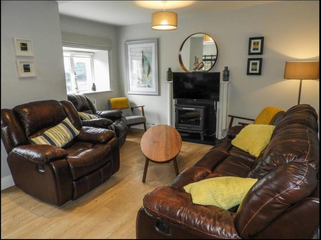 a living room with leather furniture and a fireplace at Cheerful 3 bed in the heart of Fethard village in Fethard on Sea