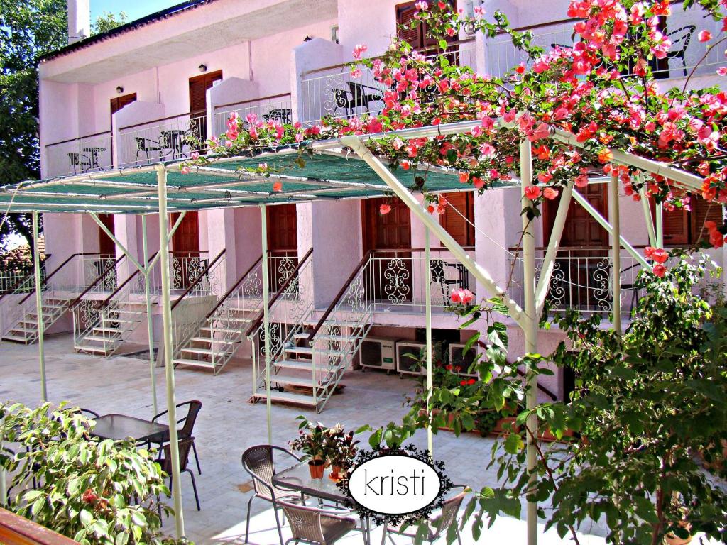 a building with tables and chairs and pink flowers at Kristi in Poros
