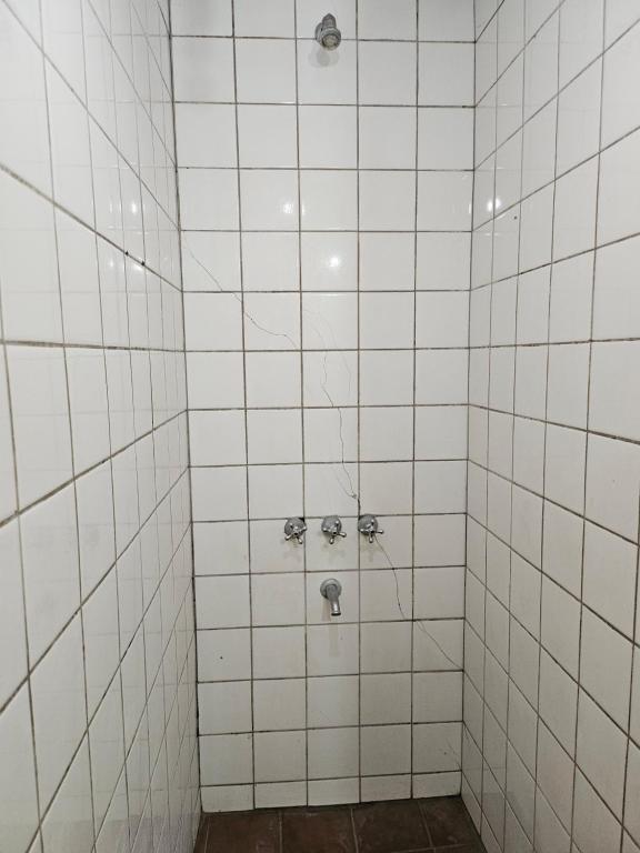 a white tiled shower with two faucets at Hostal El Buen Descanso in Rosario de Lerma