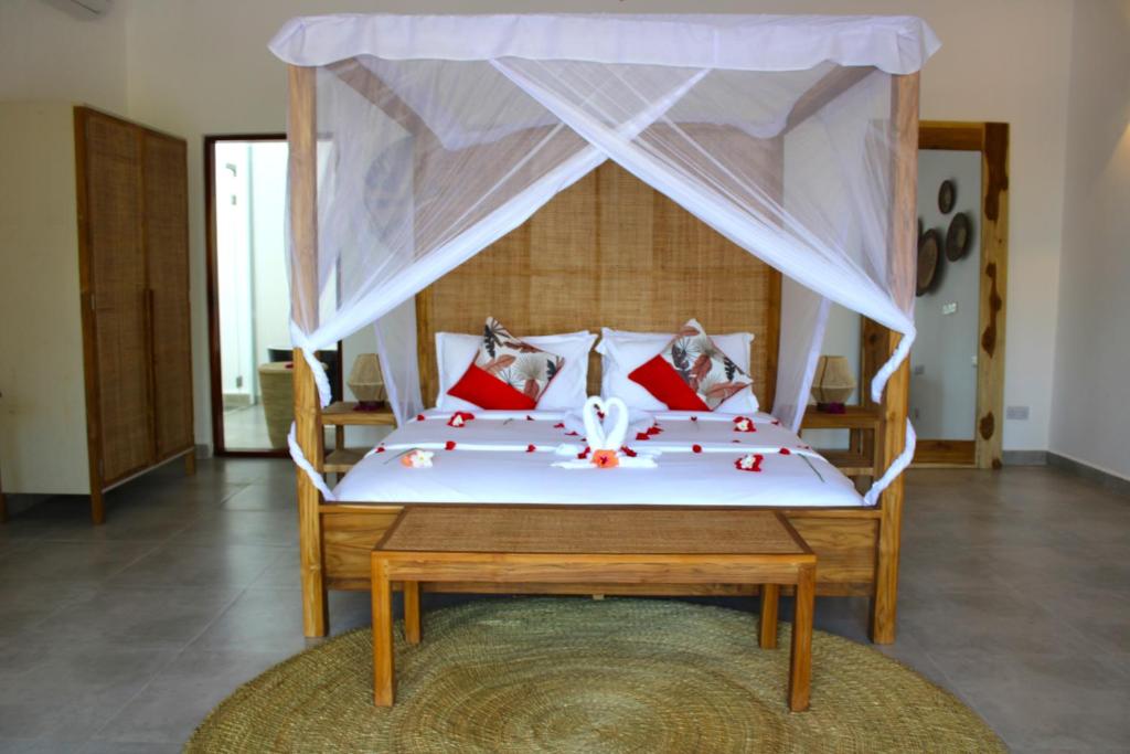 Kivuli Beach Resort Paje في باجي: غرفة نوم بسرير ومخدات حمراء ومظلة