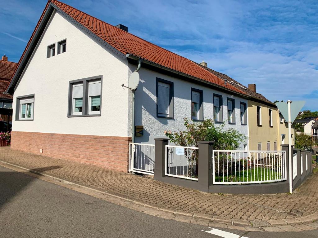 a white house with a fence on a street at Ferienwohnung Bella in Hühnerfeld
