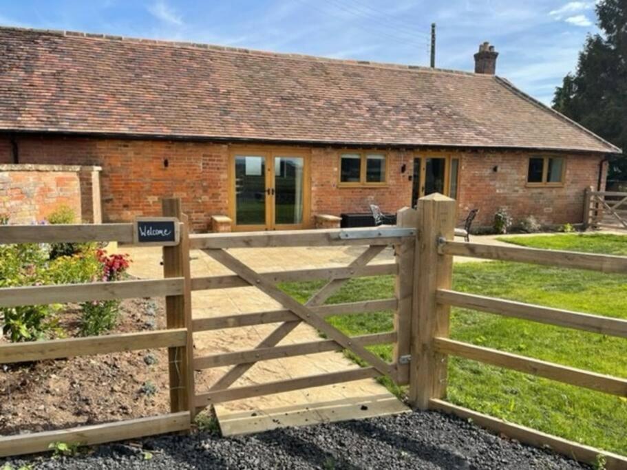 um portão de madeira em frente a uma casa em The Old Dairy. A beautifully converted barn with stunning views em Charlecote