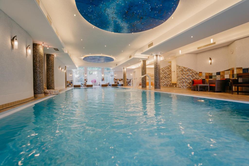 a swimming pool in a hotel with a domed ceiling at Hotel Waldkrug in Delbrück