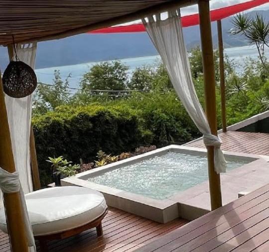 uma banheira de hidromassagem sentada num deque de madeira com uma cadeira em Villa Villagio di Mare em Ilhabela