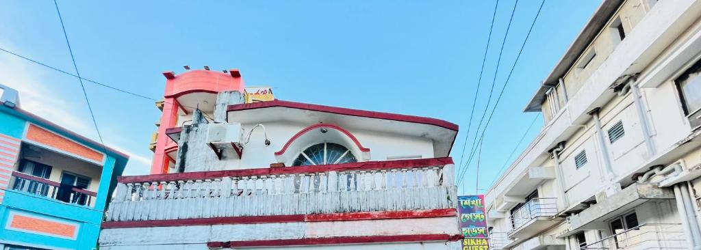 a red and white building in the middle of buildings at Sea pebbles in Digha