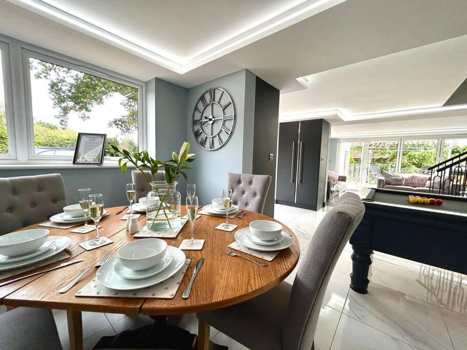 uma mesa de jantar com cadeiras e um relógio na parede em Moonsticks, Modern & Well Presented 5 Bed House em Spixworth