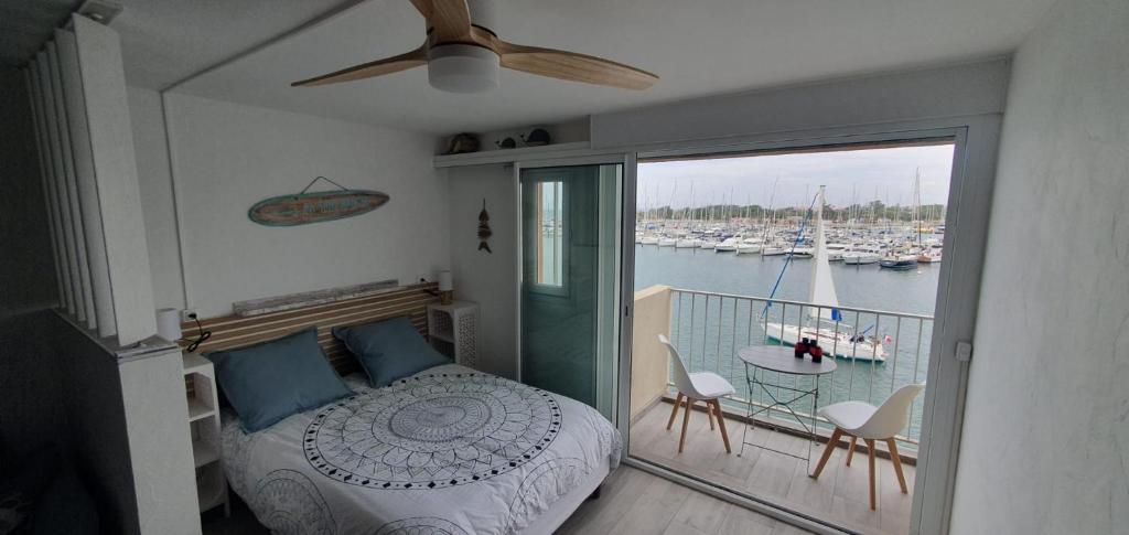 une chambre avec un lit et un balcon avec des bateaux dans l'établissement Appartement avec balcon, vue Mer, Piscine, Parking, au Cap d'Agde