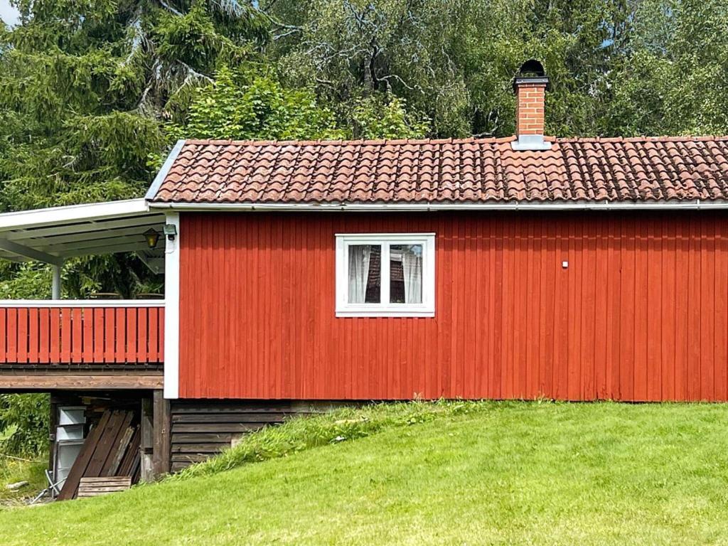 une maison rouge avec une fenêtre blanche dans un champ dans l'établissement Holiday home MOLKOM, à Molkom