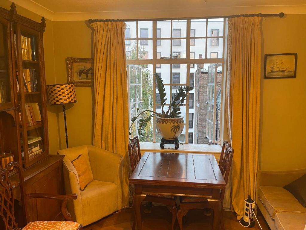 comedor con mesa, silla y ventana en Chelsea Manor Studio, en Londres