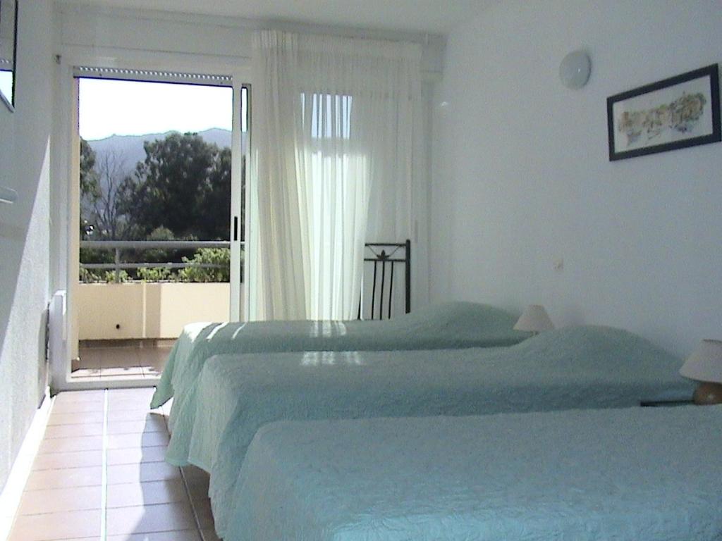 a bedroom with two beds and a large window at RESIDENCE LES TERRASSES in Calvi