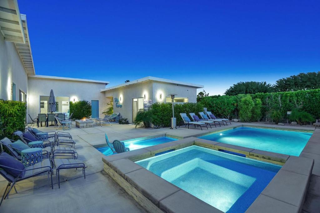 einen Pool in einem Garten mit Stühlen und einem Haus in der Unterkunft Deja Blue in Palm Springs