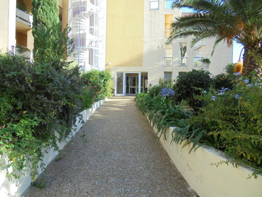 a walkway in front of a building with plants at RESIDENCE LES TERRASSES in Calvi