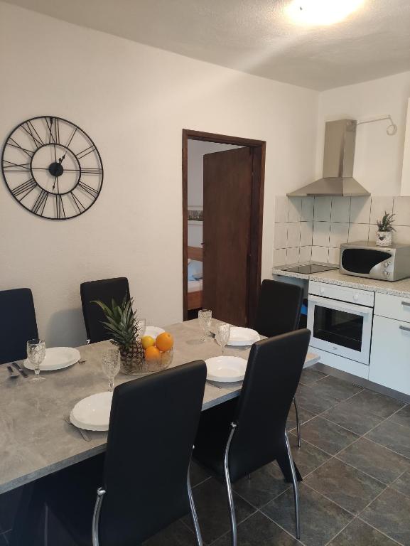 eine Küche mit einem Tisch mit Stühlen und einer Uhr an der Wand in der Unterkunft Apartmani Paraiso in Sevid