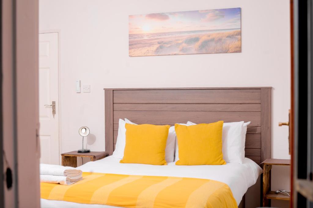 um quarto com uma cama grande e almofadas amarelas em Entire 2 Bed, 5 mins 2 Game City, Netflix & Ps4 em Gaborone