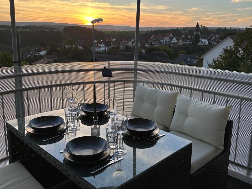 a table with plates and wine glasses on a balcony at CloudCabins No 1 - Traumblick im Herzen des Schwarzwaldes in Dornstetten