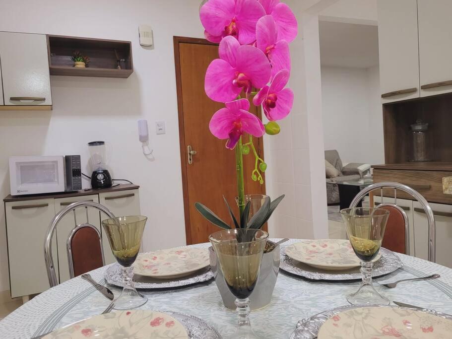 uma mesa com dois pratos e um vaso com flores cor-de-rosa em Apê 301 *AMPLO *até 6 pessoas * Ótimo p/ empresas. em Juiz de Fora