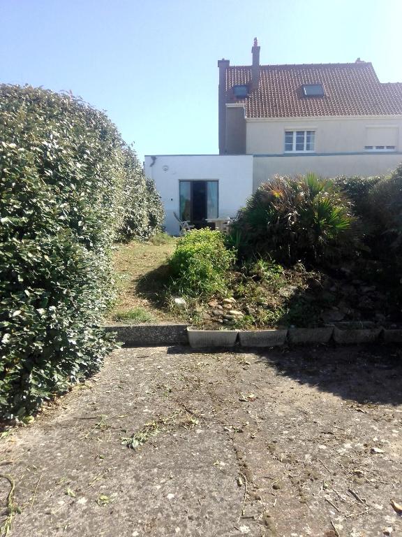 une maison blanche avec un bâtiment en arrière-plan dans l'établissement L'appartement, à Audresselles