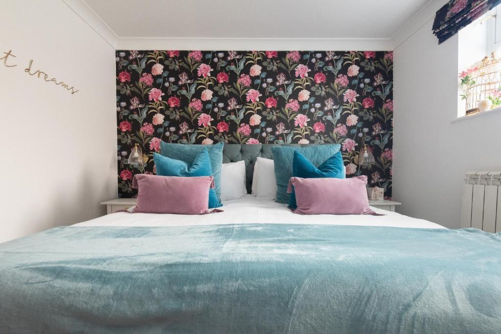 a bedroom with a large bed with pink and blue pillows at Beaumont House in Royal Tunbridge Wells