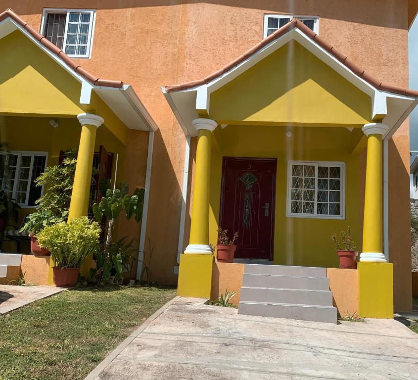 ein Haus mit gelben Säulen und einer Tür in der Unterkunft TOWNHOUSE GET-a-WAY in Mandeville
