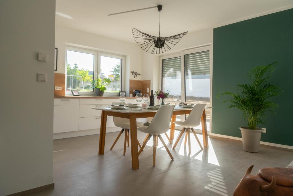 eine Küche mit einem Tisch und Stühlen sowie einer grünen Wand in der Unterkunft HAMA Design Homes Paderborn 4 Apartments in Paderborn