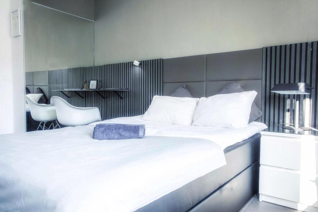 1 dormitorio con 1 cama blanca grande y 2 sillas blancas en Charmantes Studio Apartment in Bestlage im Stadtzentrum mit Balkon & self checkin - City Loft 3 -, en Colonia