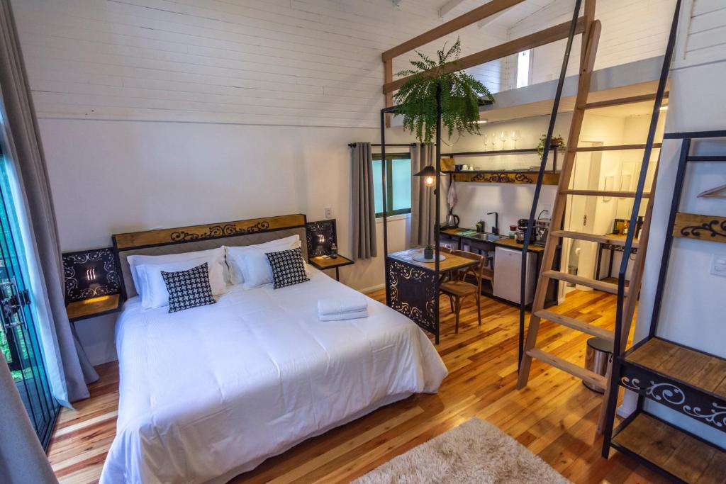 a bedroom with a large white bed and a desk at Lofts Kayser Haus in Urubici