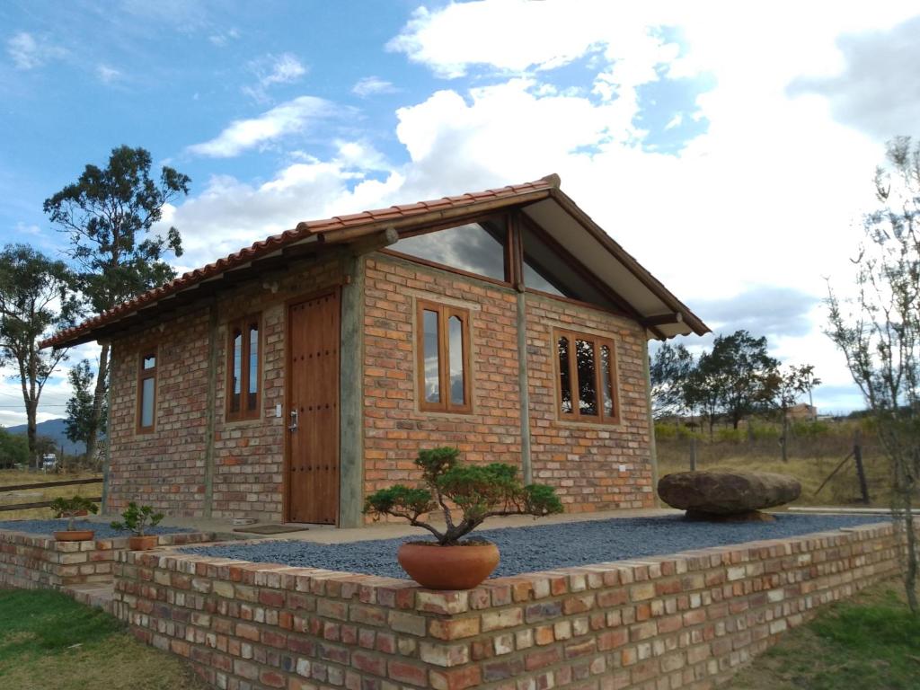 ein kleines Backsteinhaus an einer Backsteinmauer in der Unterkunft Cabaña lagovilla in Villa de Leyva