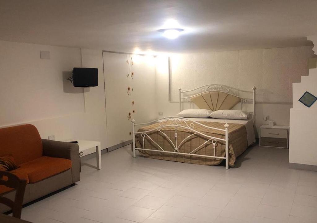 - une chambre avec un lit, un canapé et une télévision dans l'établissement B&B IL GIRASOLE, à Maddaloni