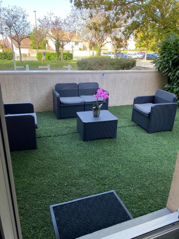 een patio met banken, een tafel en bloemen bij Logement entier chambre+salon + jardin & terrasse in Les Ulis