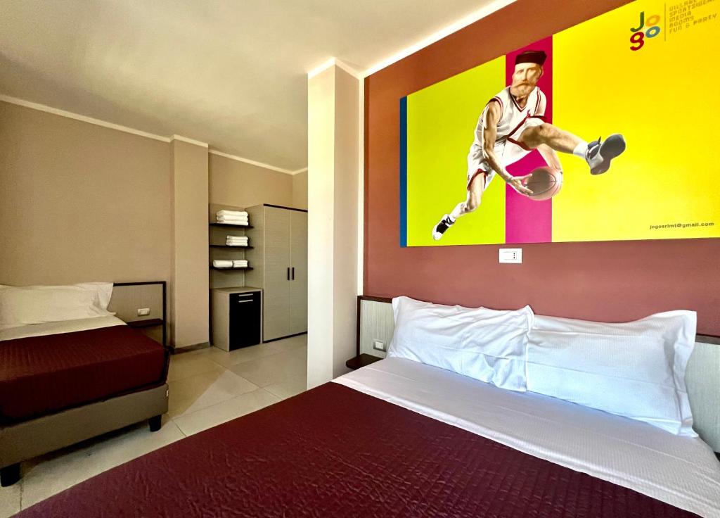 1 dormitorio con 1 cama y una pintura de un jugador de baloncesto en Jogo Rooms en Matera