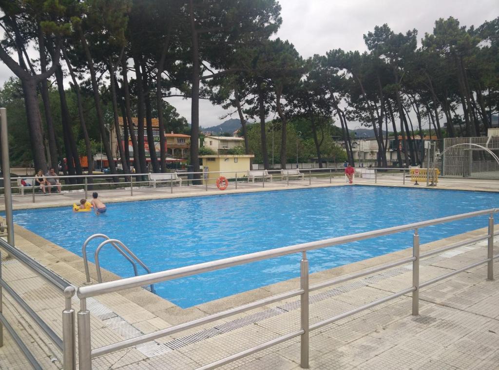 una gran piscina azul con gente en ella en El piso de Nore, en Vigo