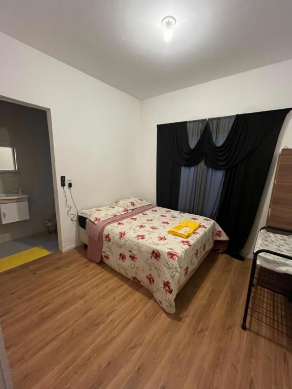 a small bedroom with a bed and a window at Suíte Hostel Curitiba in Curitiba