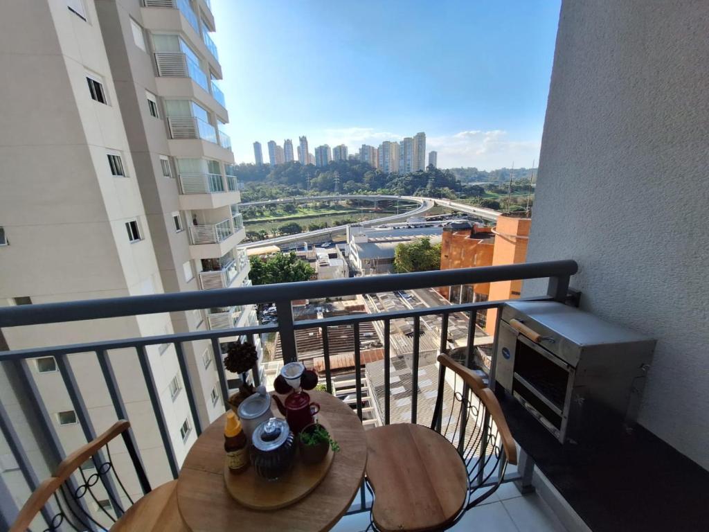 einen Balkon mit einem Tisch und einem TV auf einem Gebäude in der Unterkunft Ponte Laguna, Pq Burle Marx, Apto 1 dorm e Varanda in São Paulo