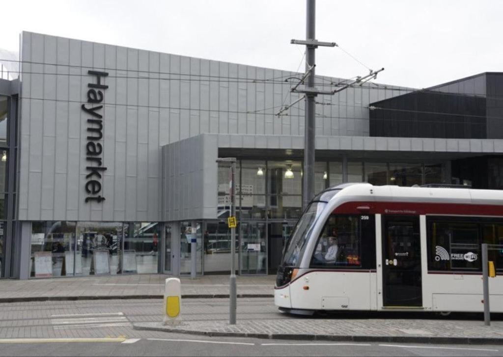 a red and white tram in front of a building at Haymarket Station Rooms in Edinburgh