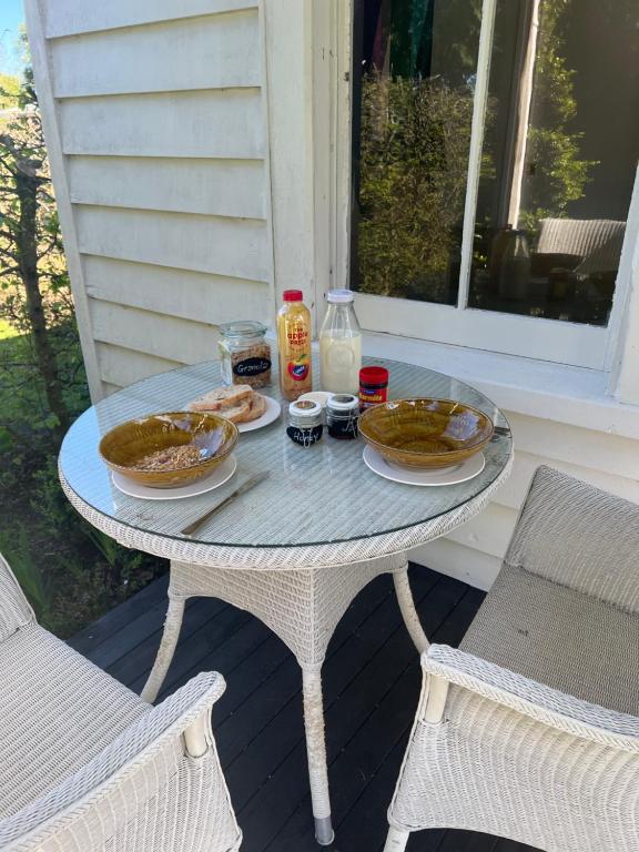 a table with two plates of food on a porch at Matamata Historic Cottage- The Wash-House in Matamata