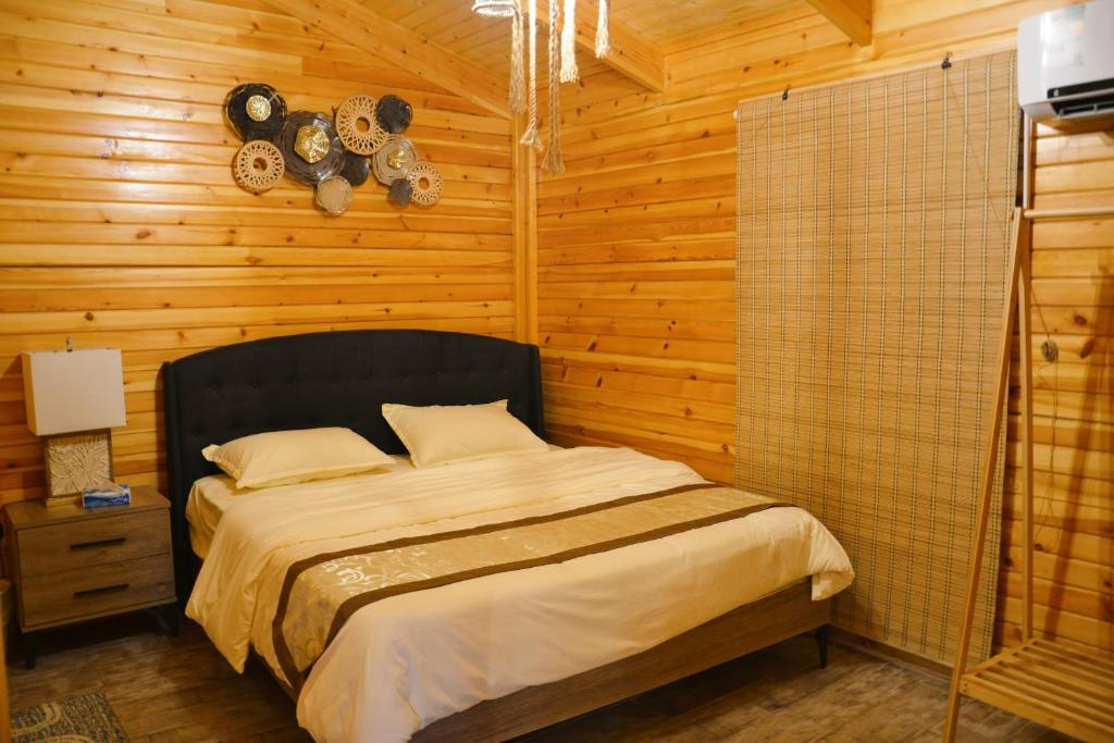ein Schlafzimmer mit einem Bett in einem Holzzimmer in der Unterkunft شاليهات الأكواخ الثلاثة in Khalij Salman