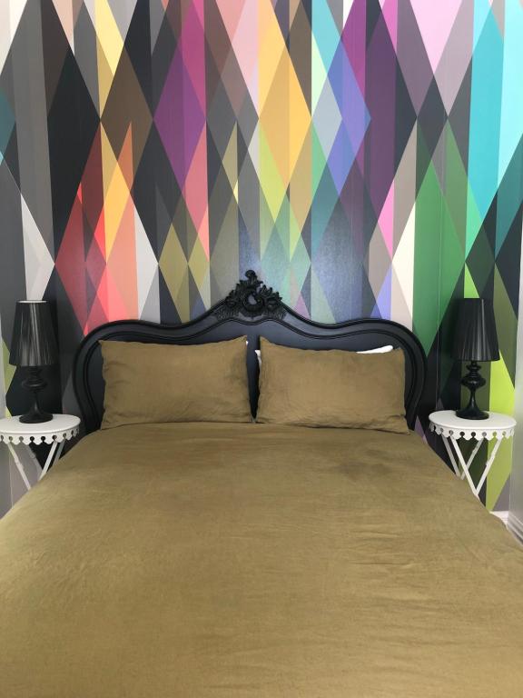 a bedroom with a bed with a colorful wall at Matamata Historic Cottage- The Wash-House in Matamata