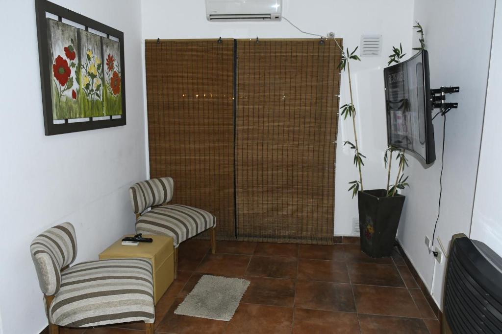 sala de estar con 2 sillas y TV en Alojamiento Las Camelias en Concordia