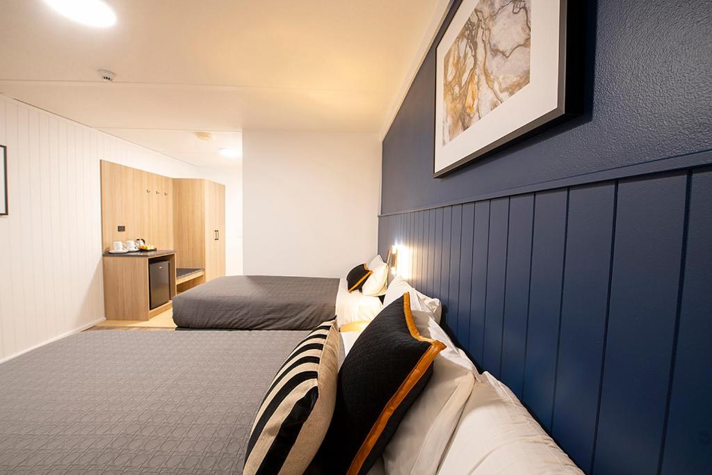 a bedroom with two beds and a blue wall at Southend Hotel in Sydney