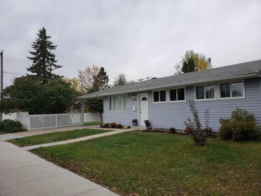 a white house with a yard and a driveway at Sweethome - 10 min to Rogers Place & so much more in Edmonton