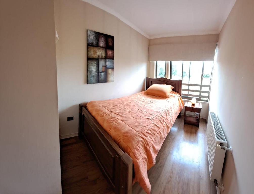 Un dormitorio con una cama con una manta naranja. en Lorena, en Concepción
